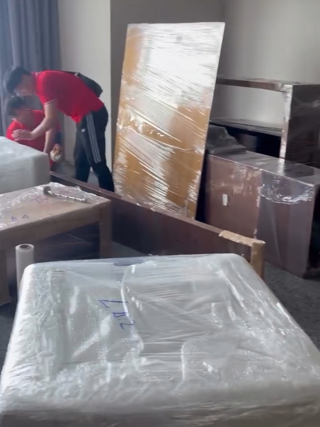 Kỹ thuật viên Thành Hưng đang quấn màng PE bảo vệ tủ gỗ